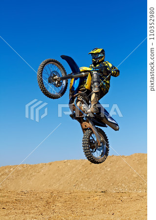 Man, motorcycle or dirt bike rally as professional rider in action danger competition, fearless or race. Male person, transportation or fast mountain adventure or blue sky, challenge or driving stunt 110352980