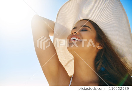Loving the sun on my skin. Closeup shot of a beautiful young woman spending some time at the beach. 110352989