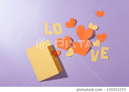 Flat lay of a card, the word LOVE and paper hearts arranged on a pastel purple background. Empty space for anniversary text design. View from above. Flat lay of a card, the word LOVE and paper hearts arranged on a pastel purple background. Empty space for anniversary text design. View from above. 110353255