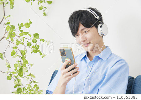 Man listening to music on smartphone at home 110353385