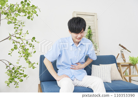 A man with stomach pain at home 110353390
