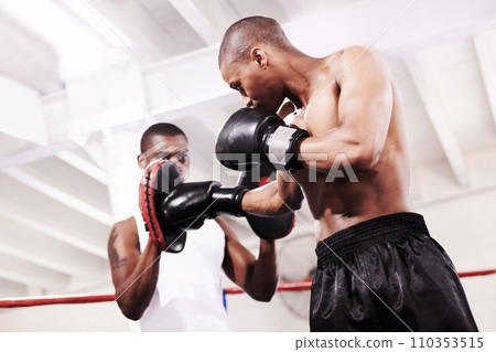 Black man, boxing and personal trainer in ring fight at gym for workout, exercise or indoor self defense training together. African male person, boxer or sparing partner preparing sports competition Black man, boxing and personal trainer in ring fight at gym for workout, exercise or indoor self defense training together. African male person, boxer or sparing partner preparing sports competition 110353515