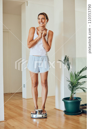 Ive lost that last bunch of pounds. Full length shot of an attractive young woman looking ecstatic while standing on a weight scale. 110353790