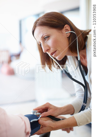Listening intently to the heartbeat. Closeup of a mature nurse checking the blood pressure and listening to the pulse of her patient. 110353908