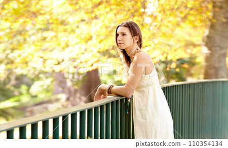 Woman, thinking or park by fence in autumn on holiday vacation in countryside, nature or France, Garden, view or calm female person with peace outdoors for fresh air, wellness or break to relax 110354134