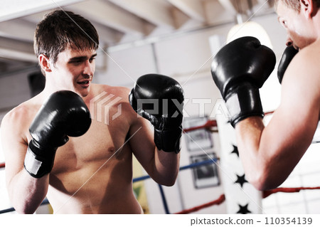 Fight, man and boxer with coaching in gym together for fitness, power strike and training challenge. Strong hit, boxing and athlete in ring with personal trainer, action and confidence in competition 110354139