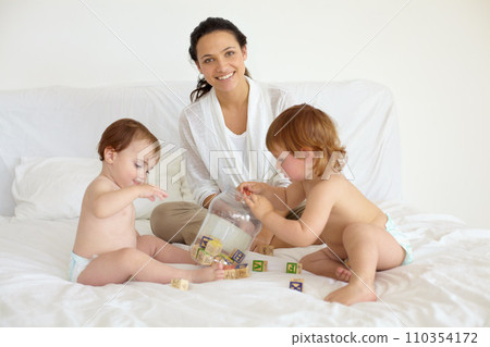 Happy, toys and portrait of mother with babies on the bed playing for child development at home. Smile, love and young mom with wooden building blocks for learning with kids in bedroom at house. Happy, toys and portrait of mother with babies on the bed playing for child development at home. Smile, love and young mom with wooden building blocks for learning with kids in bedroom at house. 110354172