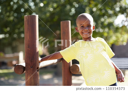 African boy, portrait and playground at kindergarten, outdoor and sunshine for playing, games and freedom. Child, school garden or park with smile, happy and development in summer, nature or academy 110354373