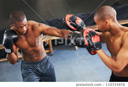 Fighting, coaching and boxer with personal trainer for fitness, power or training challenge. Strong body, spar partner and black man in gym with fist up, workout and confidence in competition boxing. 110354856