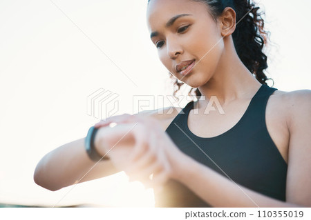 Whats my time looking like. an attractive young female athlete checking her smartwatch while out for a run in the city. 110355019