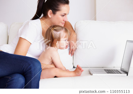 Family, laptop or streaming with a mom and baby on a sofa in the living room of a home for entertainment. Computer, movie or childcare with a woman parent and toddler girl in an apartment together 110355113