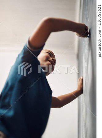 When their imagination takes flight, limitless possibilities open up. a young boy writing on a blackboard at home. 110355621