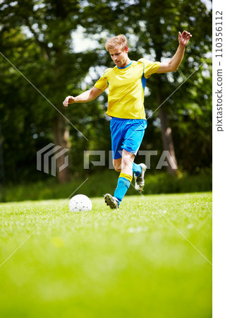 Sports, man and a soccer player kicking a ball on a field for training, a game or match on a green pitch. Health, fitness or exercise and a young athlete playing football for freedom with energy Sports, man and a soccer player kicking a ball on a field for training, a game or match on a green pitch. Health, fitness or exercise and a young athlete playing football for freedom with energy 110356112