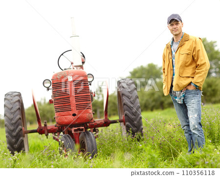 My tractor and I are in this together. Full length portrait of a farmer standing next to his tractor in a field. My tractor and I are in this together. Full length portrait of a farmer standing next to his tractor in a field. 110356118