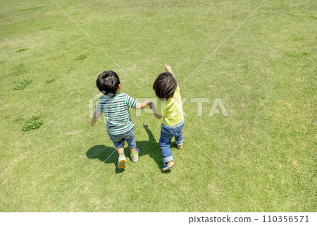 Rear view of boys playing in the park square 110356571