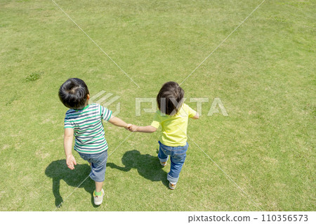 Rear view of boys playing in the park square 110356573