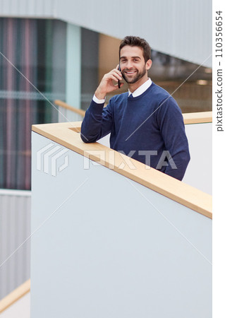 Alls well when my clients are happy. Portrait of a young businessman talking on a cellphone in an office. 110356654