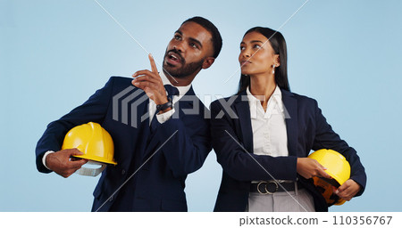 Business people, architect and pointing in vision for building or construction against a blue studio background. Man and woman in engineering or project plan with hard hat for safety on mockup space 110356767