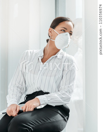 Will business ever be the same again. a masked young businesswoman looking out of a window in a modern office. 110356974