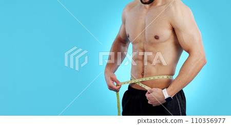 Man, body and tape measure in weight loss, bodybuilding or diet isolated on a blue studio background. Closeup of male person, athlete or bodybuilder measuring waist for workout or results on mockup 110356977