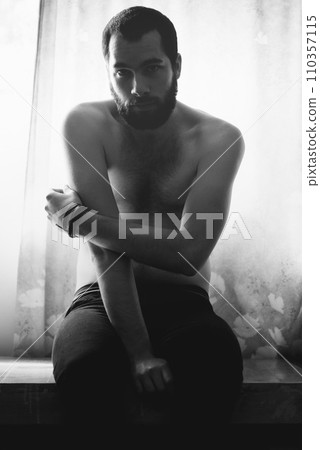Man, bedroom and portrait with thinking and creativity with black and white and beard at home. Art, shadow and male model sitting in a house with a problem and lonely from grief and monochrome 110357115
