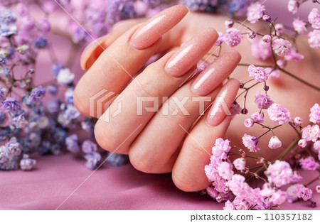 Female hands with pink nail design hold gypsophila flowers. Female hands with pink nail design hold gypsophila flowers. 110357182