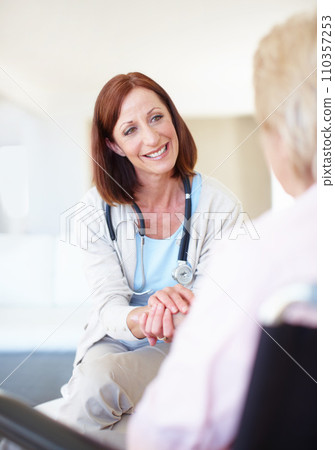 A reassuring presence when her patients are in need. Mature nurse consoles an elderly patient with kind words while holding her hand. 110357253