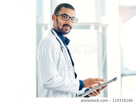 Patient info at the tap of an icon. Portrait of a young doctor using a digital tablet in a modern hospital. Patient info at the tap of an icon. Portrait of a young doctor using a digital tablet in a modern hospital. 110358186