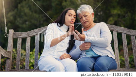 Phone, senior or mother with woman on bench in nature reading news on social media in retirement. Online gossip, mature parent or daughter for together in park or garden as a family with mobile app Phone, senior or mother with woman on bench in nature reading news on social media in retirement. Online gossip, mature parent or daughter for together in park or garden as a family with mobile app 110359015