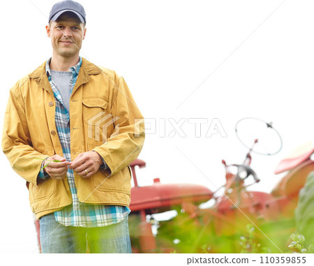 The happiest life is a simple one. Portrait of a farmer standing in a field with his tractor parked behind him - Copyspace. 110359855