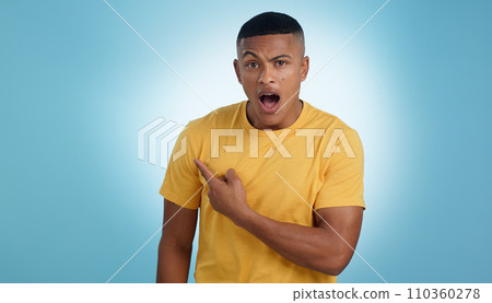 Pointing, shock and portrait of man in a studio with mockup for marketing, advertising or promotion. Surprise, wow and young male person with a show hand gesture isolated by blue background. 110360278
