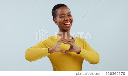 Happy black woman, portrait and heart hands for love, care or romance against a gray studio background. Face of African female person or model showing like emoji, shape or romantic gesture on mockup 110360378
