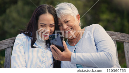 Senior, mother and woman with smartphone on bench, nature and laughing for social media meme on retirement. Mature parent, older daughter and technology in park for online comedy and love in garden 110360763