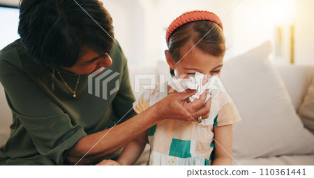 Grandmother, sick kid and sneeze in home living room for allergy, covid or virus on sofa. Grandma, girl child and tissue for cold, flu and bacteria, disease and care or mature woman help blowing nose Grandmother, sick kid and sneeze in home living room for allergy, covid or virus on sofa. Grandma, girl child and tissue for cold, flu and bacteria, disease and care or mature woman help blowing nose 110361441