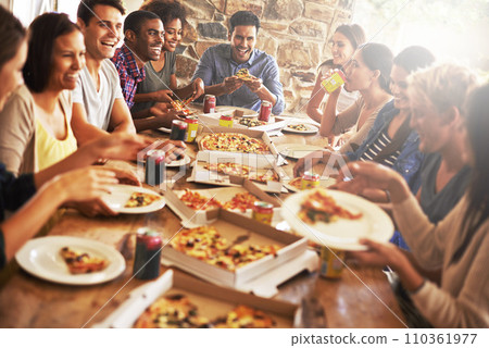 Catching up over great zza. a group of friends enjoying pizza together. 110361977