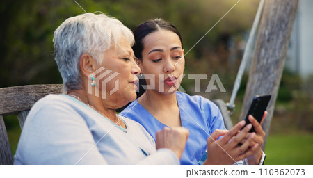 Outdoor, bench and nurse with old woman, smartphone and connection with social media, conversation and internet. Pensioner, outdoor and caregiver with elderly person, cellphone and typing with email 110362073