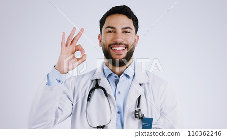 Happy man, portrait and doctor with OK sign for healthcare approval against a gray studio background. Face of male person or medical professional smile with like emoji, okay or yes for perfect health 110362246