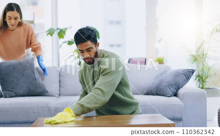 Couple, spring cleaning and gloves in home living room with teamwork for dirt, dust and bacteria with cloth. Man, woman and helping hand for furniture, hygiene and shine on wood with safety in house 110362342