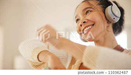Young woman, headphones and dancing in home living room, happy and freedom with music, sound or listening. Dancer girl, smile and thinking for audio streaming subscription, phone or excited in lounge Young woman, headphones and dancing in home living room, happy and freedom with music, sound or listening. Dancer girl, smile and thinking for audio streaming subscription, phone or excited in lounge 110362487