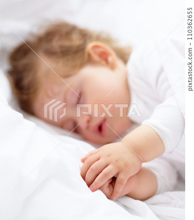 Hands, baby and kid sleeping on bed for calm break, peace and dreaming to relax at home. Tired, young child and cozy nap for newborn development, healthy childhood growth and rest in nursery room 110362655