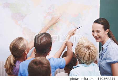 Geography can be fun. A group of children looking at a world map during geography class. 110362855