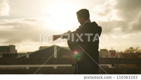 Man, stretching and fitness in city for workout, exercise or outdoor training with cloudy sky. Rear view, male person or athlete in flare, body warm up or arm stretch getting ready in an urban town 110363203