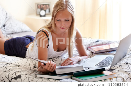 Books, laptop and female student on a bed for learning, research or college homework assignment. Education, university and learner online in bedroom studying, reading or check exam schedule at home 110363234