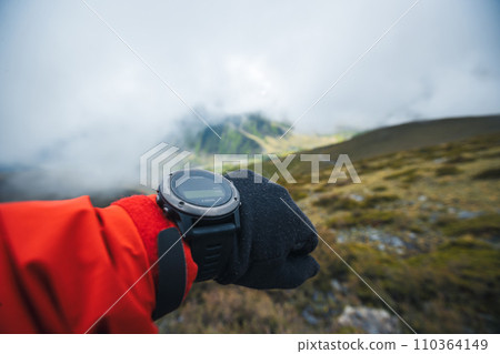 Woman hiker checking the altitude on smartwatch on mountain peak 110364149