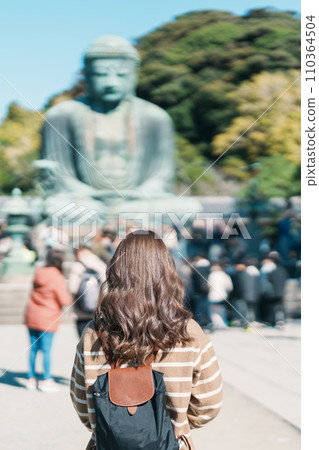 Woman tourist Visiting in Kamakura, Kanagawa, Japan. happy Traveler sightseeing the Great Buddha statue. Landmark and popular for tourists attraction near Tokyo. Travel and Vacation concept Woman tourist Visiting in Kamakura, Kanagawa, Japan. happy Traveler sightseeing the Great Buddha statue. Landmark and popular for tourists attraction near Tokyo. Travel and Vacation concept 110364504