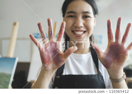 The artist creates a frame with her hands soiled with watercolor paints. 110365412