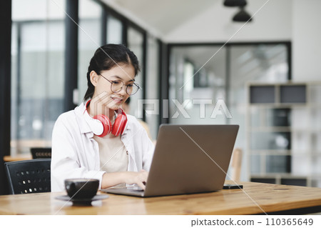 Young collage student using computer and mobile device studying online... Young collage student using computer and mobile device studying online... 110365649