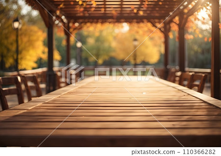 Empty wooden table top with illuminated wooden pergola in park background with bokeh autumn sunlight. Empty wooden table top with illuminated wooden pergola in park background with bokeh autumn sunlight. 110366282