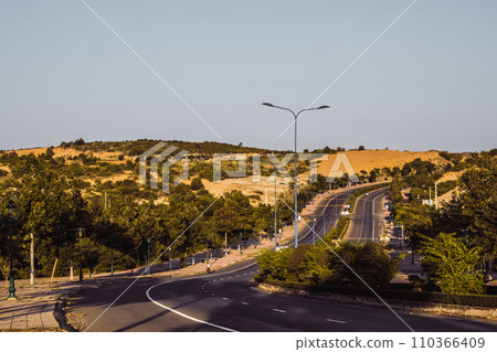 Highway curve road overpass nature landscape background dark tone mist day time street tall lanterns trees bushes sideway 110366409