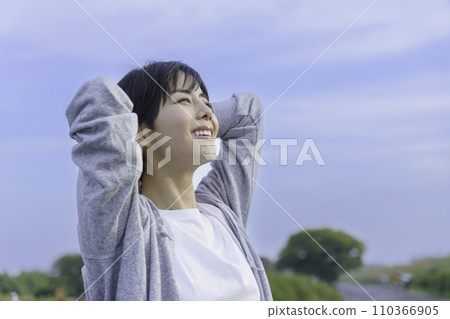 Young woman looking up at the blue sky on the bank 110366905